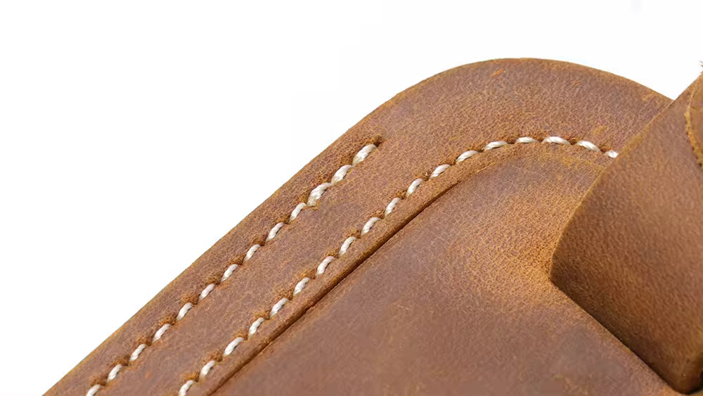 Handcrafted full grain leather luggage tag in brown, featuring white stitching and an adjustable strap with a brass buckle for secure attachment to luggage