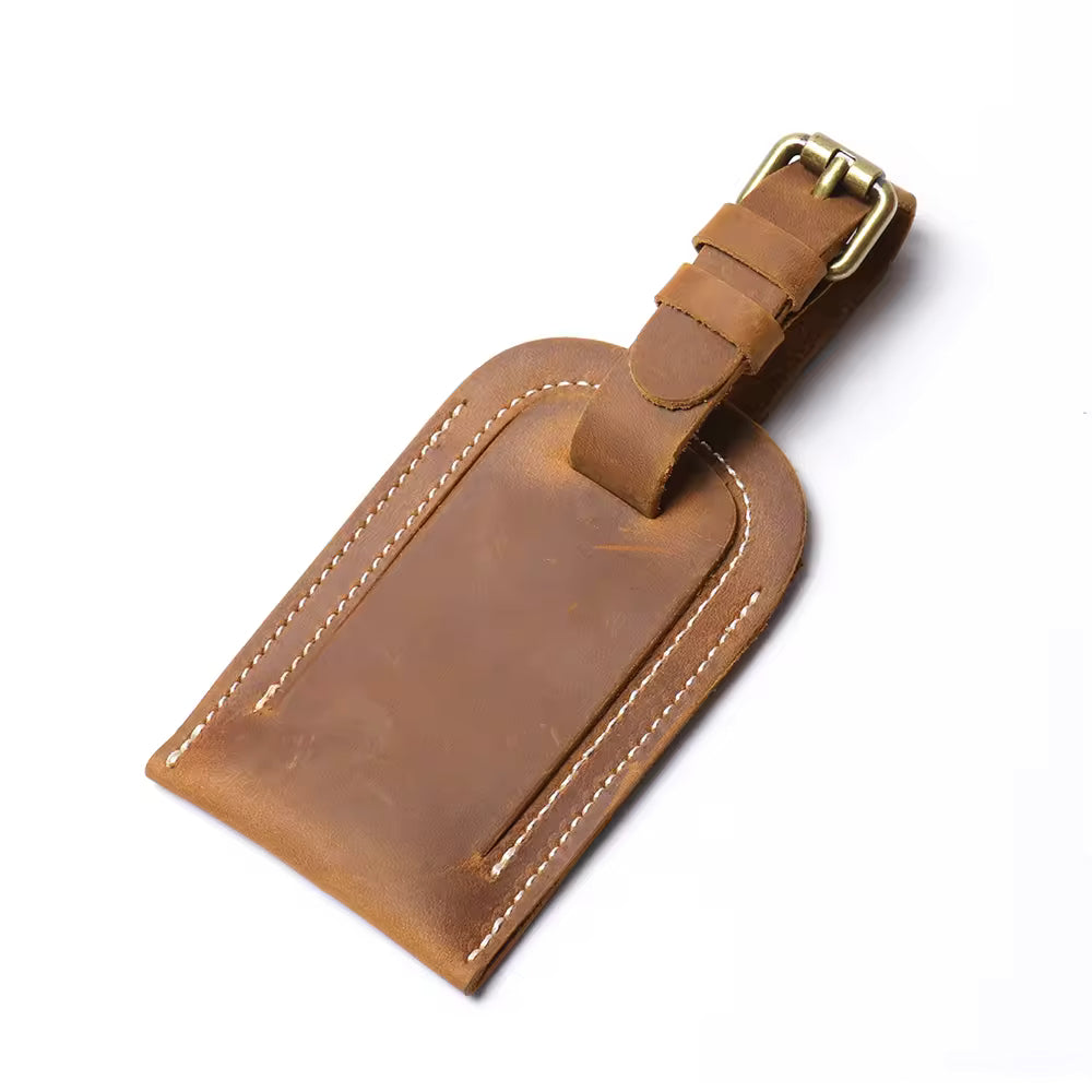 Handcrafted full grain leather luggage tag in brown, featuring white stitching and an adjustable strap with a brass buckle for secure attachment to luggage