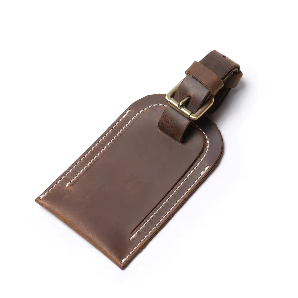 Handcrafted full grain leather luggage tag in brown, featuring white stitching and an adjustable strap with a brass buckle for secure attachment to luggage